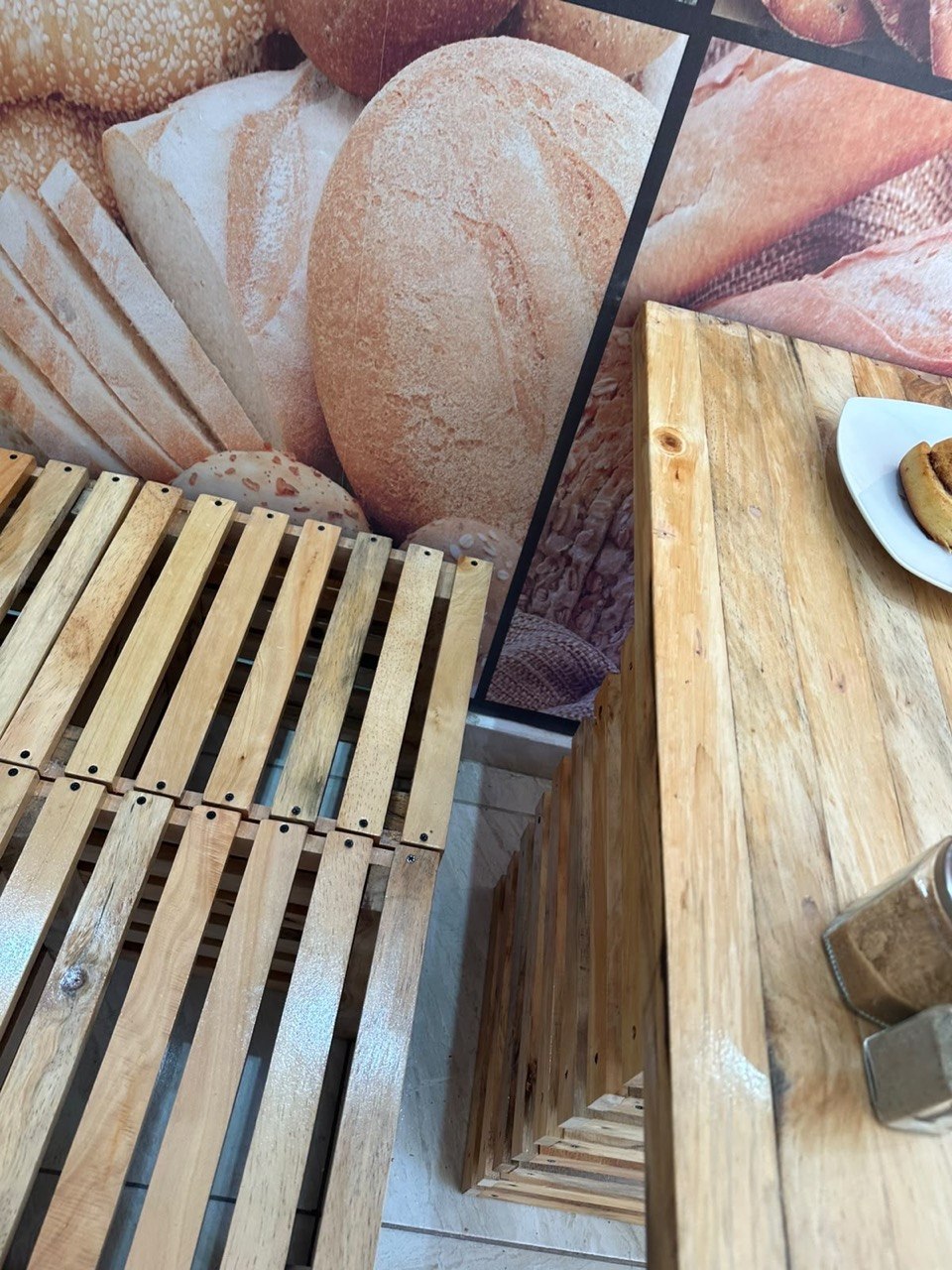 Mesa y banca de palés de madera frente al mural de panes